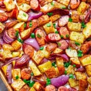 Sheet Pan Sausage And Potatoes with red onions.