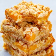 A stack of four mango oatmeal crumble bars, the top bar missing a bite.