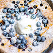 Pumpkin Blueberry Dutch Baby Pancake topped with powdered sugar and vanilla ice cream.