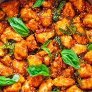 Sticky Basil Chicken in a pot topped with fresh basil.