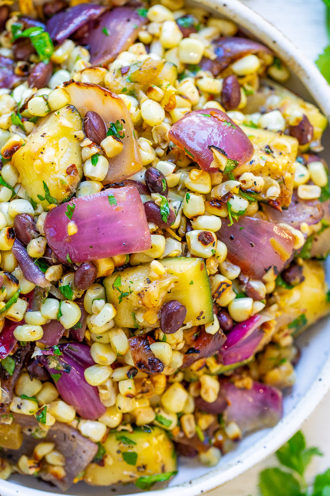 Mexican Corn and Black Bean Salad — An EASY corn salad with black beans, zucchini, red onions, cilantro, lime juice, and more!! So much Mexican-inspired FLAVOR in every bite of this family favorite recipe that's sure to be a hit!!