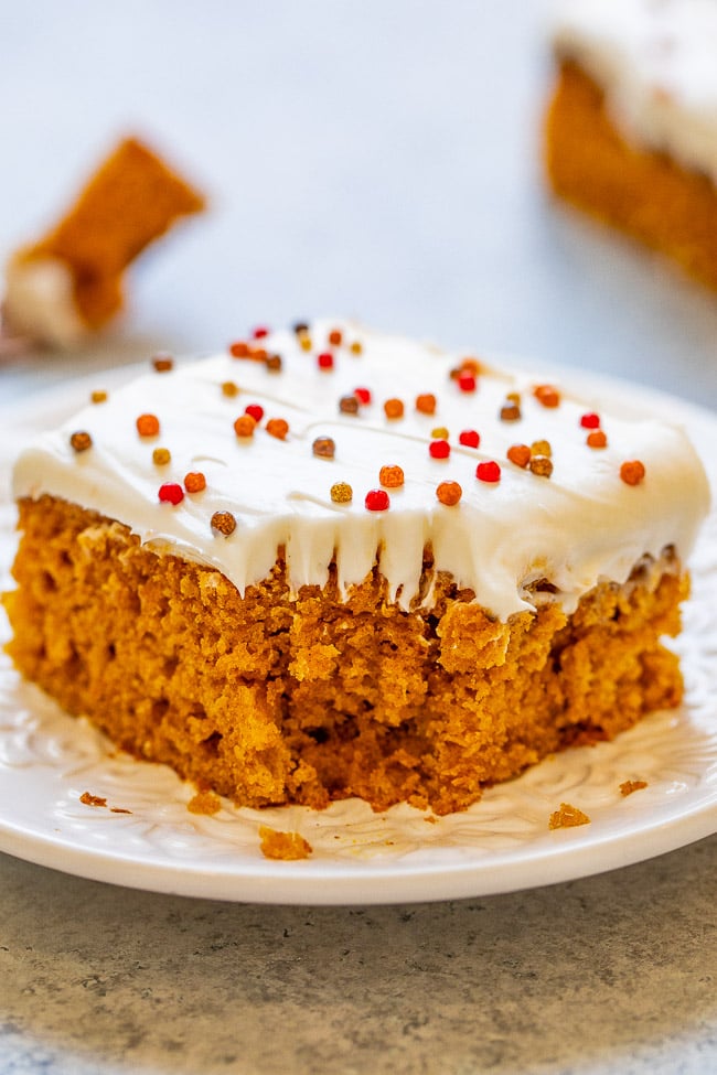 a pumpkin spice bar topped with frosting on a white plate 
