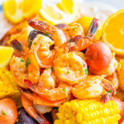 A colorful seafood boil with shrimp, corn, potatoes, and lemon slices on a plate.