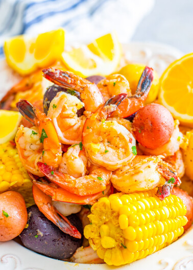 A colorful seafood boil with shrimp, corn, potatoes, and lemon slices on a plate.