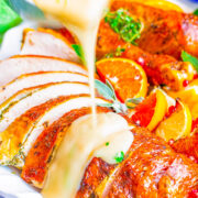 Turkey gravy being poured over sliced turkey on a plate.