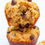 Two stacked peanut butter banana muffins stacked, the top muffin missing a bite.