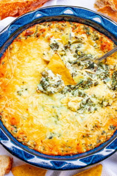 Baked Spinach Artichoke Dip in a bowl with a spoon sticking out.