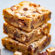 Three chocolate chip Snickers cookie bars on top of each other.