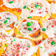 A colorful dish of scalloped potatoes garnished with red and green seasoning, suggesting a festive or holiday theme.