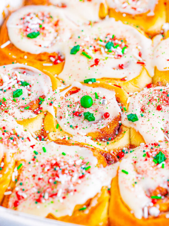 A colorful dish of scalloped potatoes garnished with red and green seasoning, suggesting a festive or holiday theme.