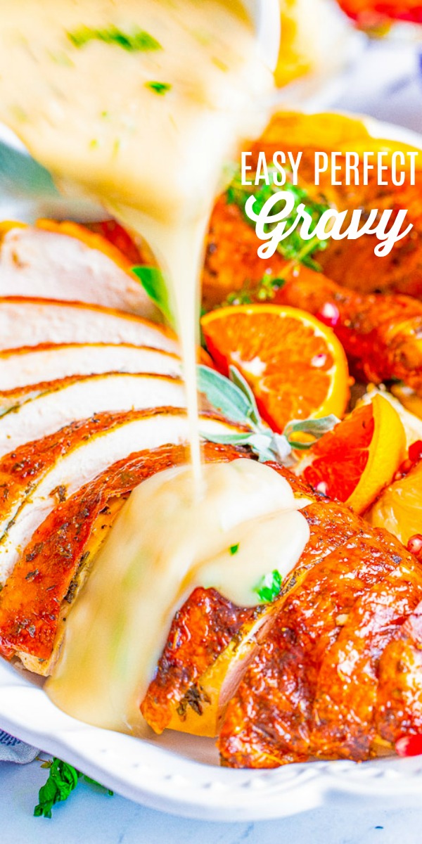 Pouring gravy over sliced roasted turkey garnished with herbs and orange slices.