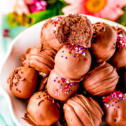 A bowl of chocolate brownie balls, the top ball missing a bite.