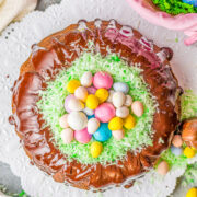 An Easter egg bundt cake topped with green coconut flakes and candy eggs.