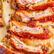 Slow cooker BBQ ribs on a parchment paper lined baking sheet.