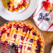 A strawberry rhubarb pie in a pan and a slice on a plate topped with ice cream.