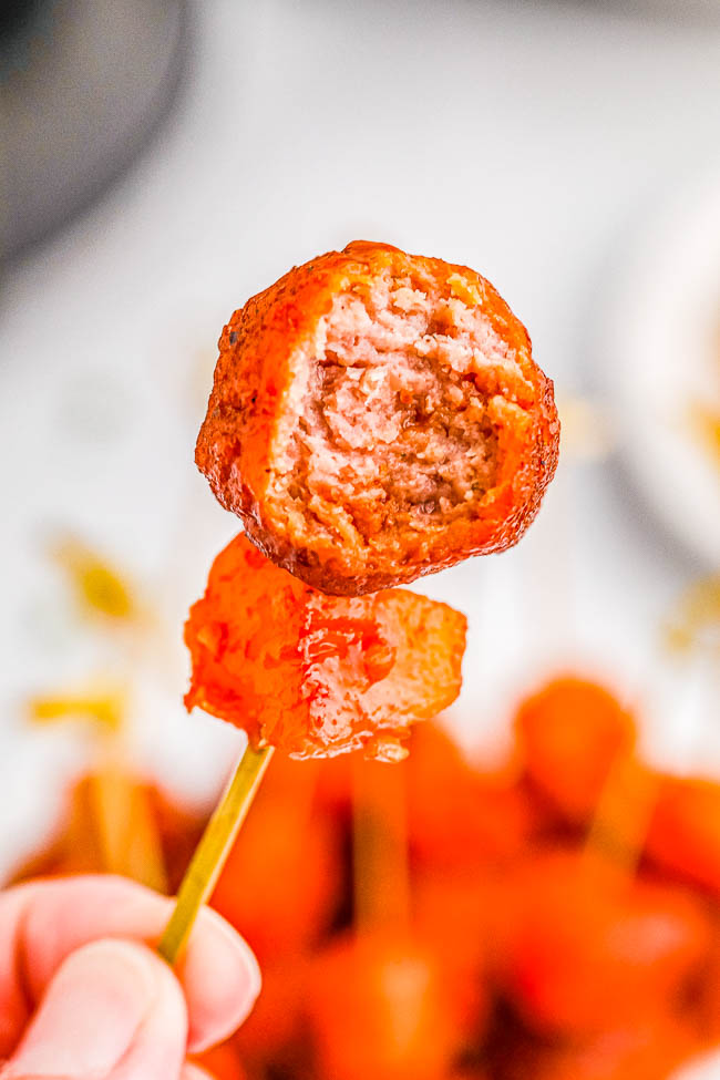 A close-up of a meatball skewered on a toothpick, showing its cooked interior.