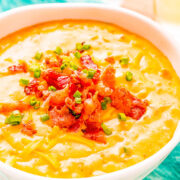 Beer Cheese Soup in a bowl topped with bacon and green onions.