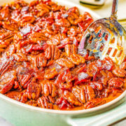 Savory Sweet Potato Casserole with Candied Bacon in a casserole dish with a slotted spoon sticking out.