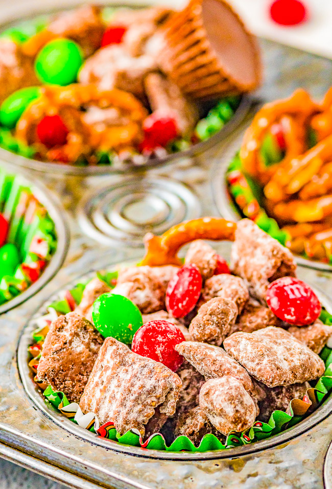 Loaded Christmas Puppy Chow - This fast, easy, no-bake holiday treat is LOADED with all the good stuff! Chocolate, peanut butter, sugar, M&Ms, peanut butter cups, and pretzels for a salty-sweet, crunchy, and addictive snack! Makes great little gifts because it keeps well and everyone LOVES it! 
