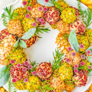 Cheese Ball Wreath - A delectable cheese ball mixture rolled in festive and colorful toppings and arranged into a wreath! A show-stopping presentation of wonderful cheese bites for your holiday parties and entertaining tables! EASY to make and can be made IN ADVANCE! No one can resist the allure of cheese!