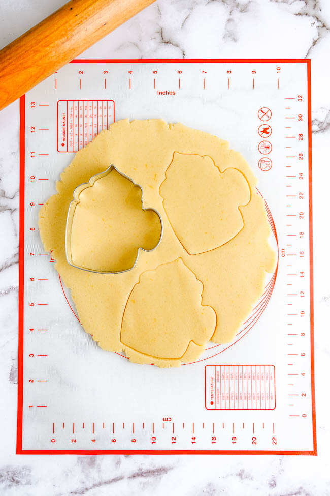 Cut-Out Coffee Cup Cookies - Soft, buttery sugar cookies cut out in the shape of coffee cups and decorated with red and white royal icing! These sugar cookies are PERFECT for Christmas as well as for wintertime parties and entertaining. No one will be able to resist these unique beauties!