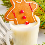 A Classic Gingerbread Man Cookie sticking out of a glass of milk.
