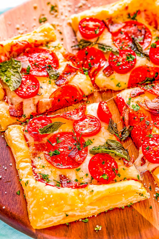 Puff Pastry Pizza - This EASY pizza is topped with oodles of cheese, pepperoni, bacon, cherry tomatoes, fresh basil, and has a puff pastry crust! Never underestimate the power of a kitchen shortcut like puff pastry on busy weeknights when you're looking for a family-friendly and kid-approved dinner recipe that's FAST to make! 