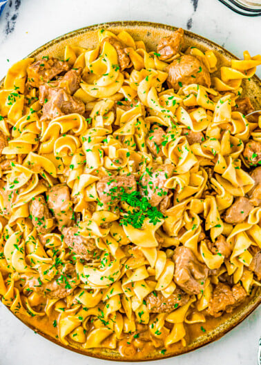 Slow Cooker Beef Stroganoff - A comfort food classic that everyone in the family LOVES! Hearty chunks of beef, rich and flavorful beef gravy, and served over a bed of warm noodles to soak up all that goodness! The EASIEST recipe for beef stroganoff ever because your Crock-Pot truly does all the work! Set it and forget it! 