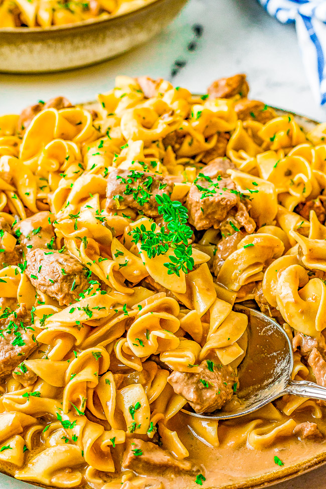 Slow Cooker Beef Stroganoff - A comfort food classic that everyone in the family LOVES! Hearty chunks of beef, rich and flavorful beef gravy, and served over a bed of warm noodles to soak up all that goodness! The EASIEST recipe for beef stroganoff ever because your Crock-Pot truly does all the work! Set it and forget it! 