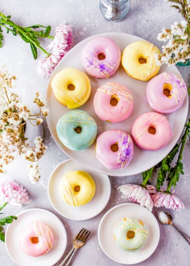 Baked Vanilla Donuts - Making donuts at home is easier than you think! Full of rich vanilla flavor in both the batter and the glaze, these donuts are a family FAVORITE. They're baked and not fried so you can have seconds! Perfect for springtime, Easter, and Mother's Day but you can change the glaze color to suit the season or your mood! 