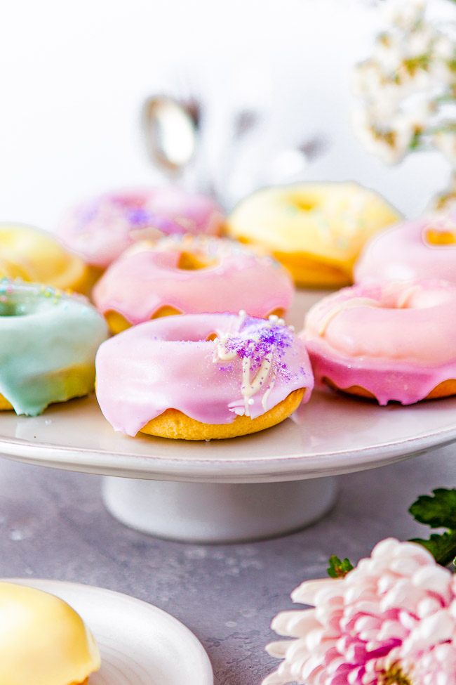 Baked Vanilla Donuts - Making donuts at home is easier than you think! Full of rich vanilla flavor in both the batter and the glaze, these donuts are a family FAVORITE. They're baked and not fried so you can have seconds! Perfect for springtime, Easter, and Mother's Day but you can change the glaze color to suit the season or your mood! 
