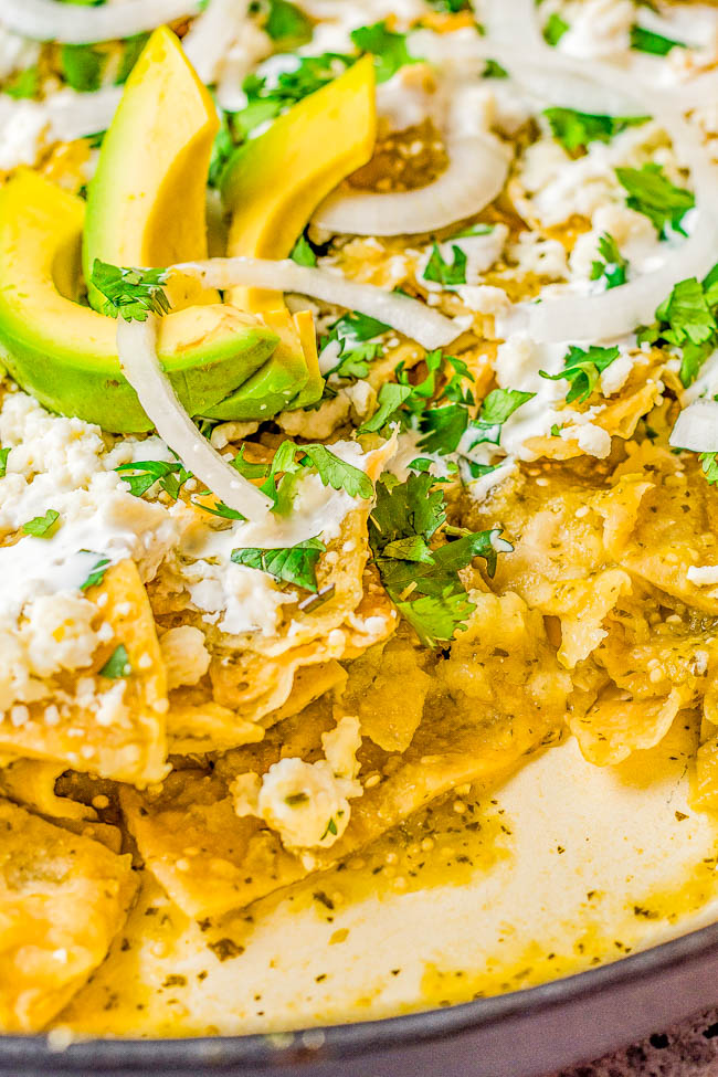 Chilaquiles Verdes - Tortilla chips are smothered in a homemade tangy tomatillo serrano chile salsa verde before being garnished to the max with avocado, queso fresco, crema, cilantro, and onion! EASY and ready in 20 minutes! They have the perfect amount of spiciness to keep you wanting just one more bite!