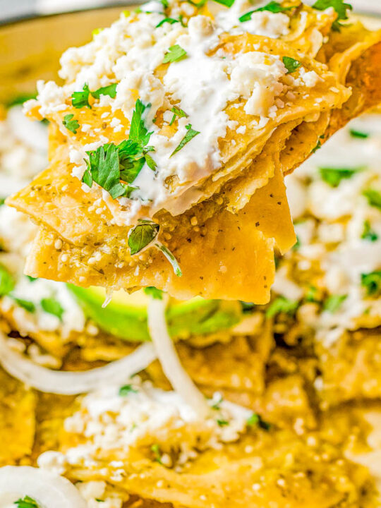 Chilaquiles Verdes - Tortilla chips are smothered in a homemade tangy tomatillo serrano chile salsa verde before being garnished to the max with avocado, queso fresco, crema, cilantro, and onion! EASY and ready in 20 minutes! They have the perfect amount of spiciness to keep you wanting just one more bite!