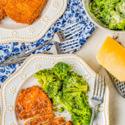 A Parmesan pork chop on a plate with broccoli.