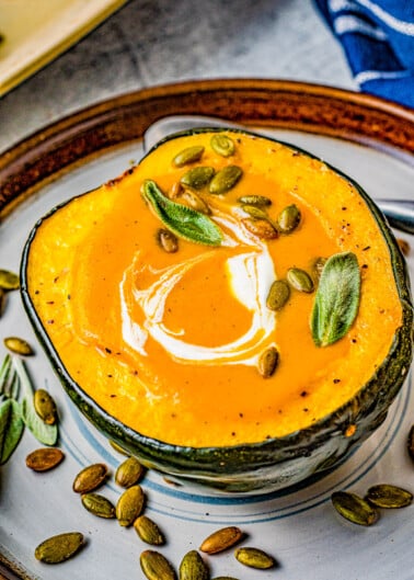 Butternut Squash Soup - Made with roasted butternut and acorn squash, sweet potatoes, carrots, sage, thyme, and more to create a gorgeous, creamy, fall-inspired soup that everyone LOVES! Great as a healthy main dish or a perfect side dish for Thanksgiving or the holidays! Serve it in acorn squash bowls for an even more festive look!