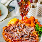 Maple glazed being spooned over a pork chop.
