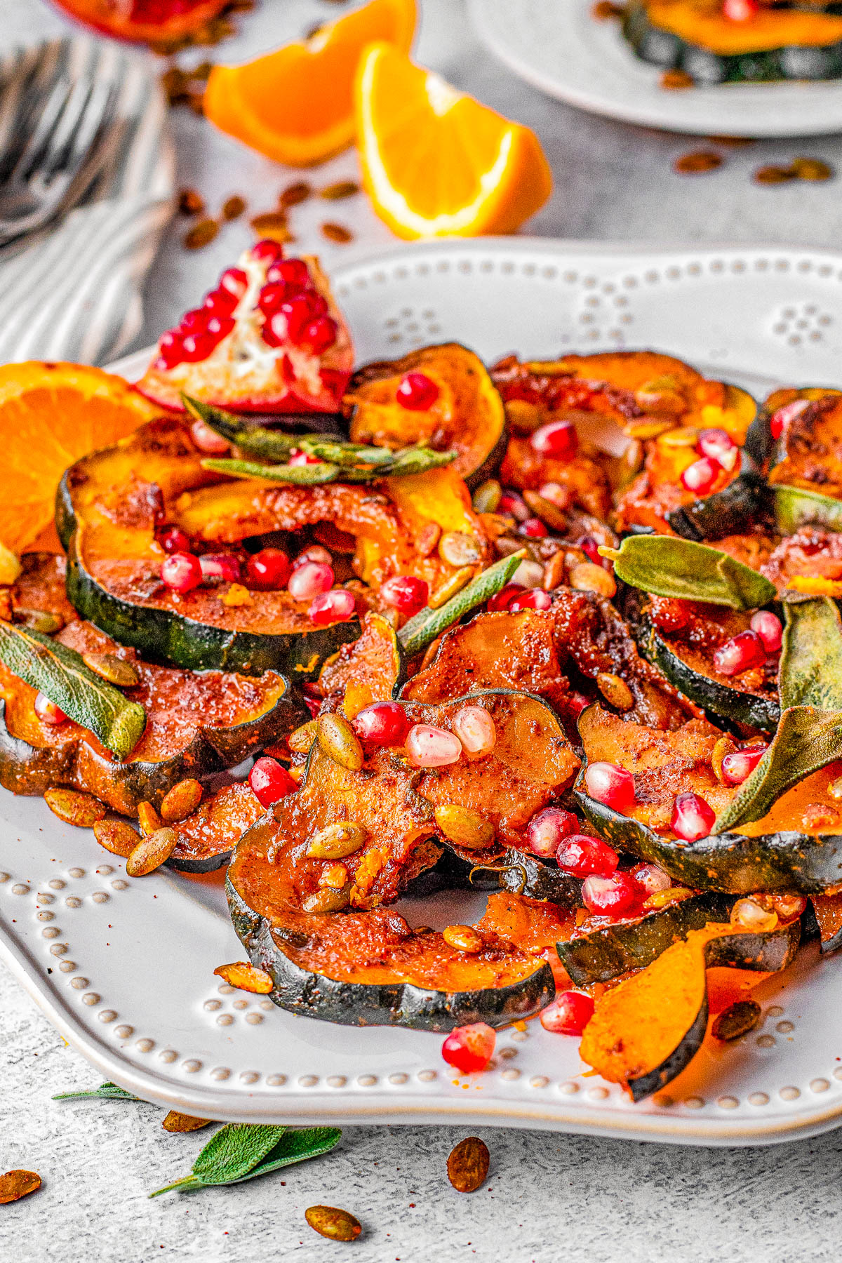 Sweet and Spicy Acorn Squash - Tender oven-roasted acorn squash is made extra fabulous with a sweet and spicy orange-infused butter sauce. It's topped with toasted sage leaves, pumpkin seeds, pomegranate arils, and a touch of orange zest for a festive touch. An EASY fall-flavored side dish that's ready in 20 minutes! Perfect for weeknight dinners or put it on your Thanksgiving or Christmas menus! 