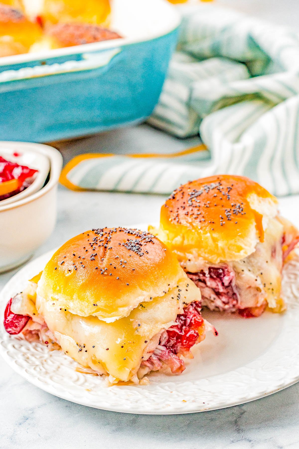 Turkey and Cheese Sliders - Juicy turkey, Swiss cheese, and cranberry sauce all nestled in soft Hawaiian rolls that are brushed with butter and topped with poppy seeds for the BEST turkey sliders! FAST, EASY, and takes advantage of leftover turkey! Deli turkey also works.