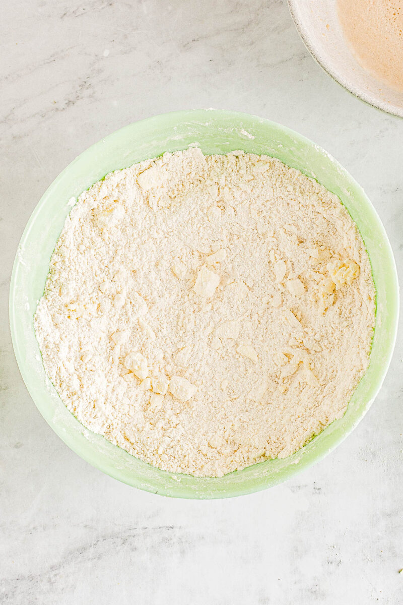 Butter cubes cut into a bowl of dry ingredients for angel biscuits.