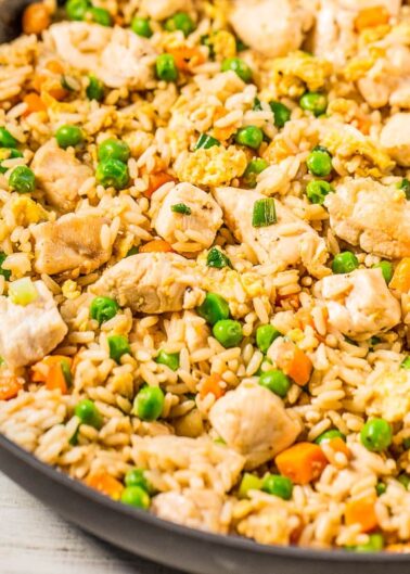 A skillet of chicken fried rice with peas, carrots, and egg.