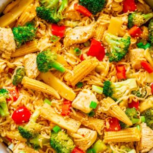A colorful stir-fry with chicken, vegetables, and noodles in a pan.