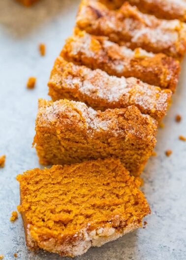 Slices of cinnamon-dusted pumpkin bread arranged in a row.