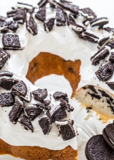 A bundt cake topped with white frosting and crushed oreo cookies.