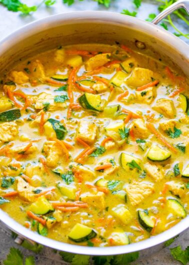A vibrant pot of creamy vegetable curry garnished with cilantro.
