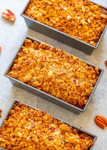 Three loaf cakes with streusel topping and pecan pieces, freshly baked.