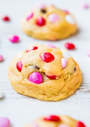 Freshly-baked cookies with pink and red candy pieces on a wooden surface.