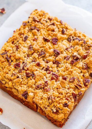 A freshly-baked crumb cake with pecan topping on parchment paper.