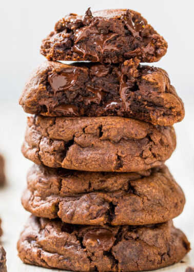 A stack of gooey chocolate cookies on a wooden surface.