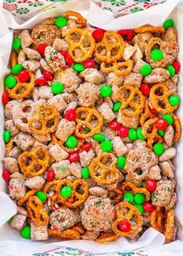 A festive bowl of puppy chow mixed with pretzels, red and green m&ms, and sprinkles.