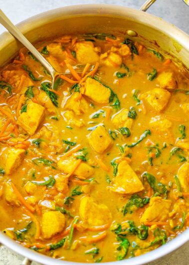 A pot of creamy chicken and vegetable curry with spinach.